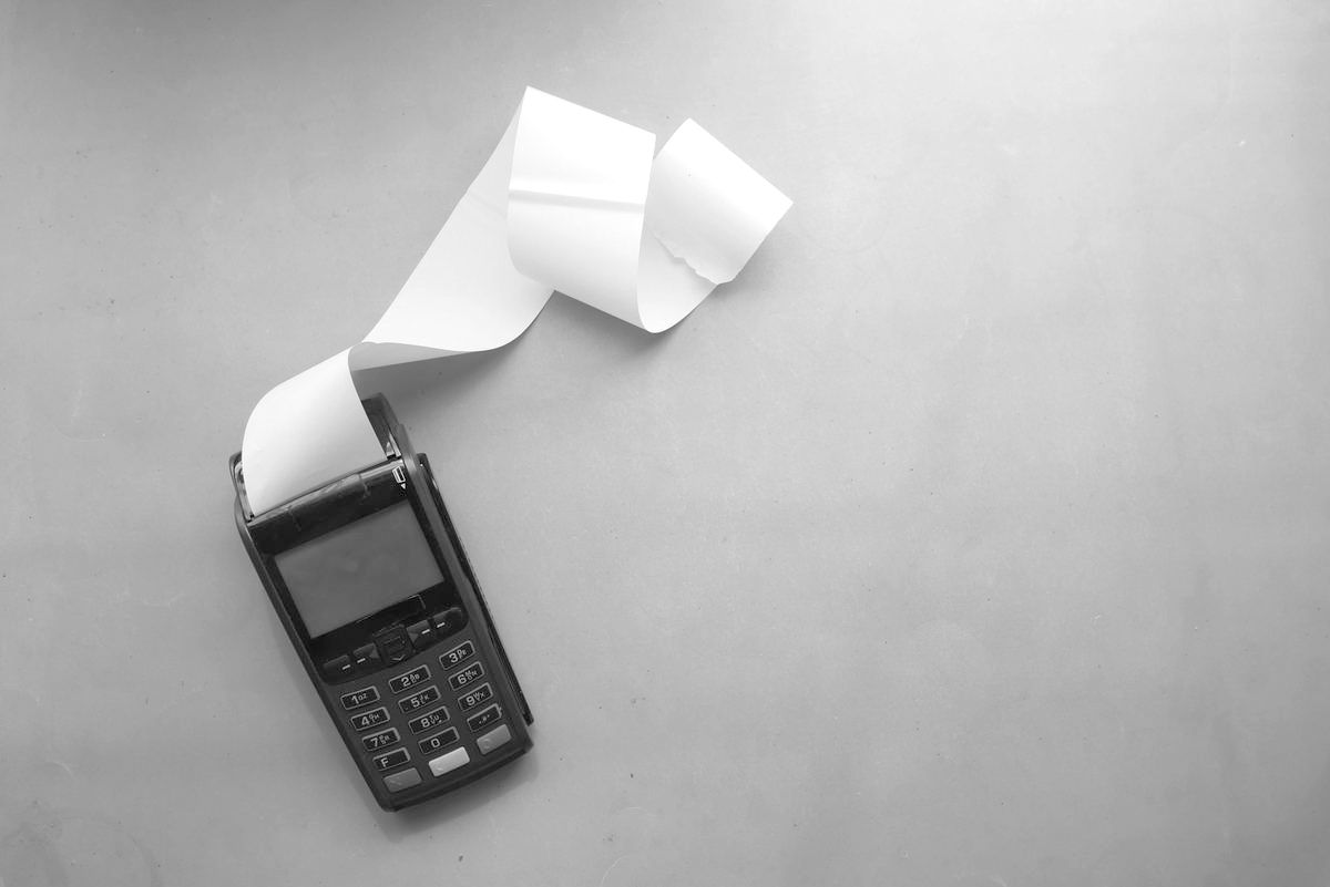 Terminale POS per i pagamenti elettronici visto dall'alto mentre stampa una lunga ricevuta